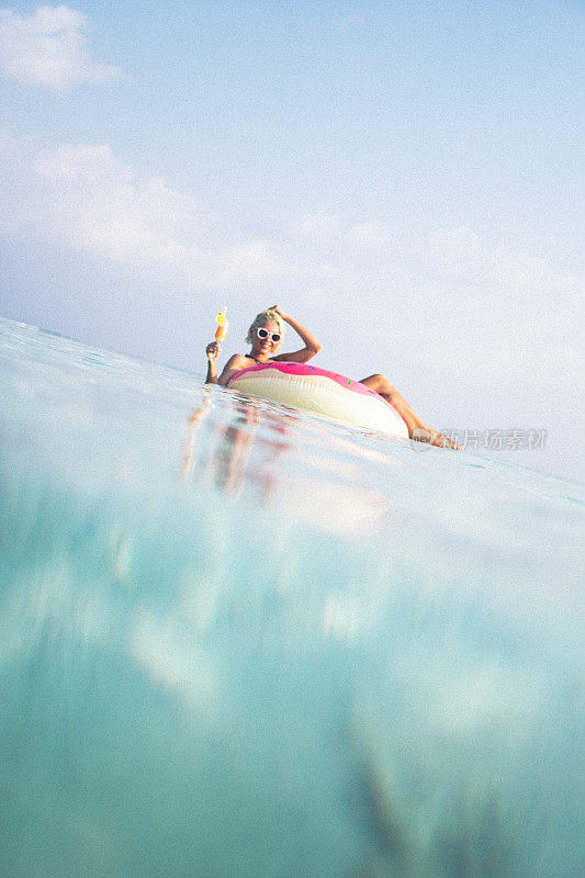 一个金发女人漂浮在马尔代夫的海洋里