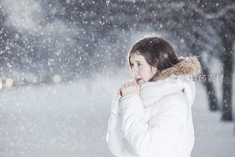 雪下穿着白色夹克的漂亮少女