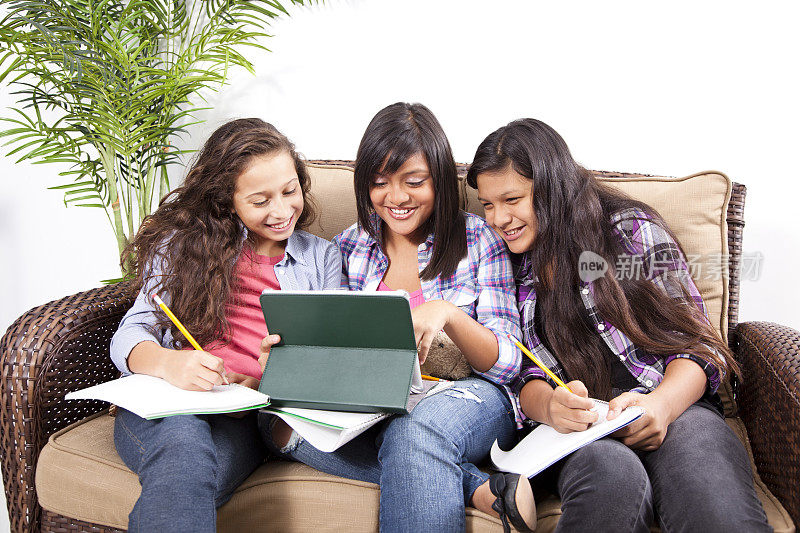 三个快乐的拉丁少女在用数码平板电脑