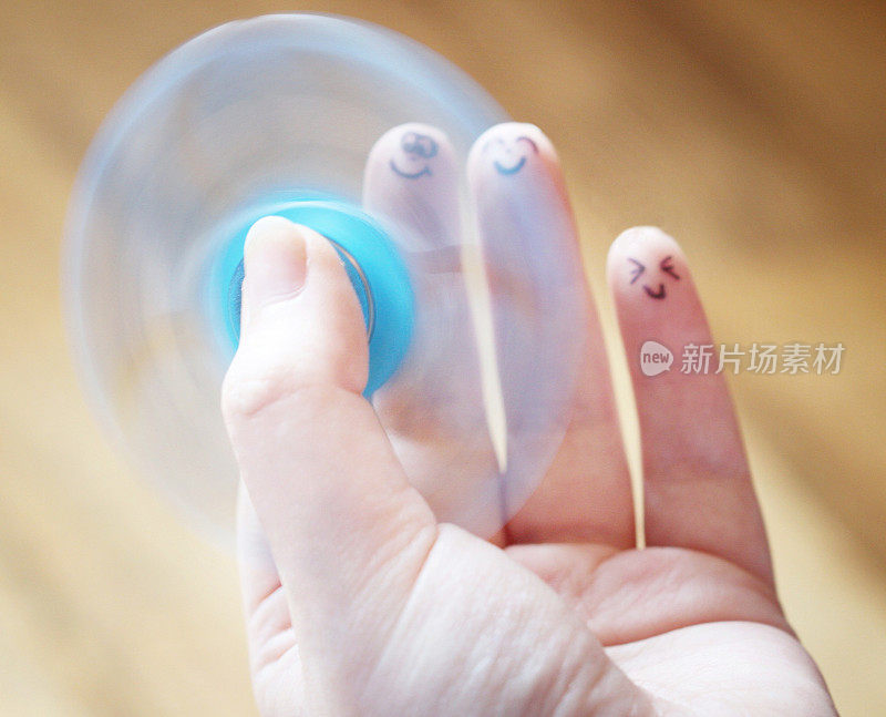 女性手握指尖陀螺玩具与脸部画在手指上