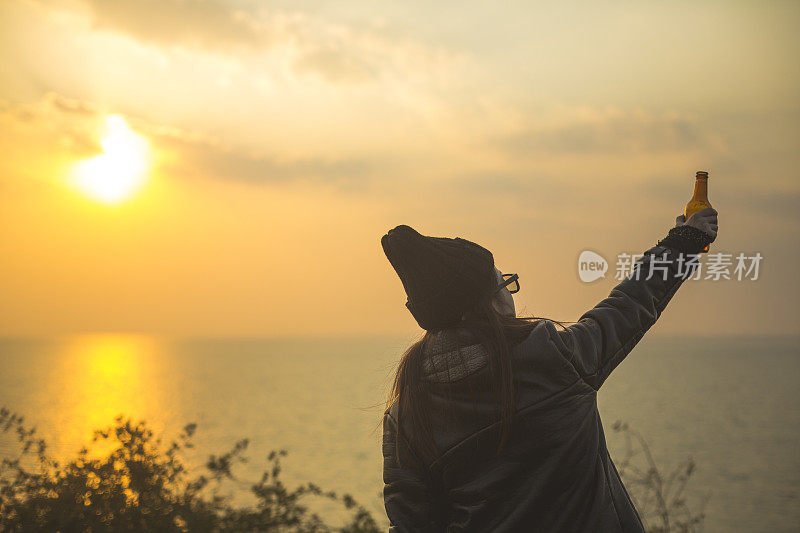 夕阳西下，年轻女子喝着啤酒