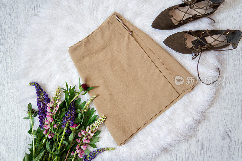 浅棕色麂皮裙和白色毛皮鞋，一束鲜花。时尚的概念