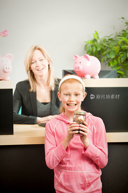 银行出纳员在零售银行柜台为小女孩客户提供储蓄服务