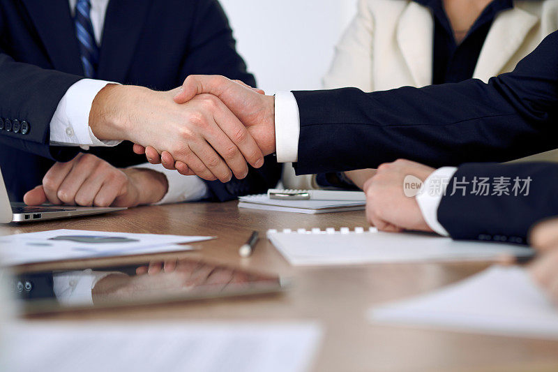 商务人士在会议或在办公室谈判握手的特写。合作伙伴因签订合同而满意