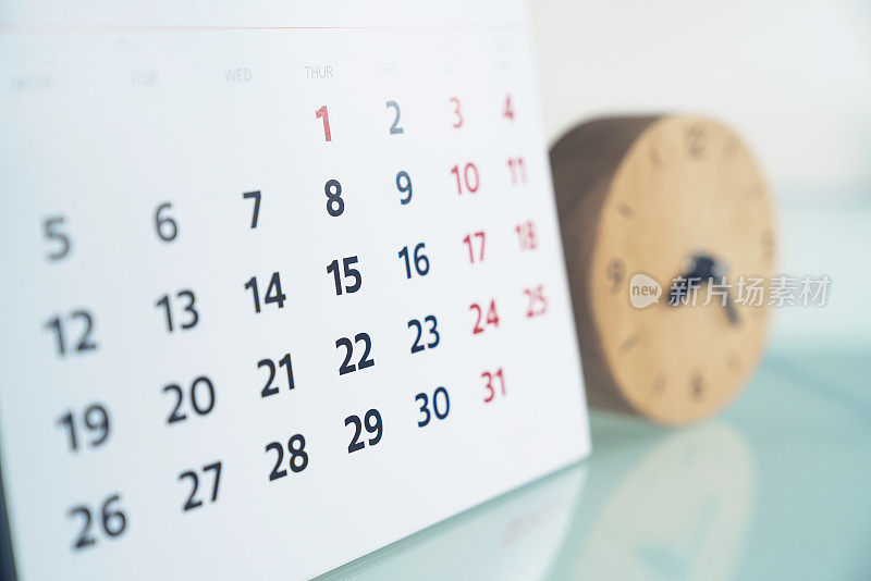 关闭的日历和时钟在桌子上，计划商务会议或旅行计划的概念