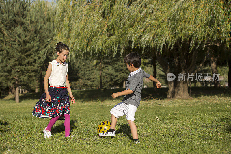 两个可爱的小孩，在夏天一起踢足球