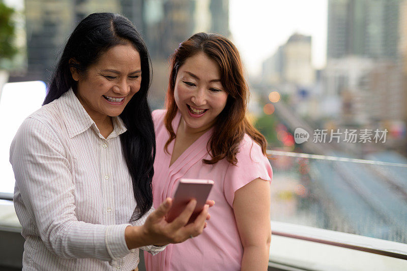 两个成熟的亚洲女性朋友的肖像反对泰国曼谷的城市