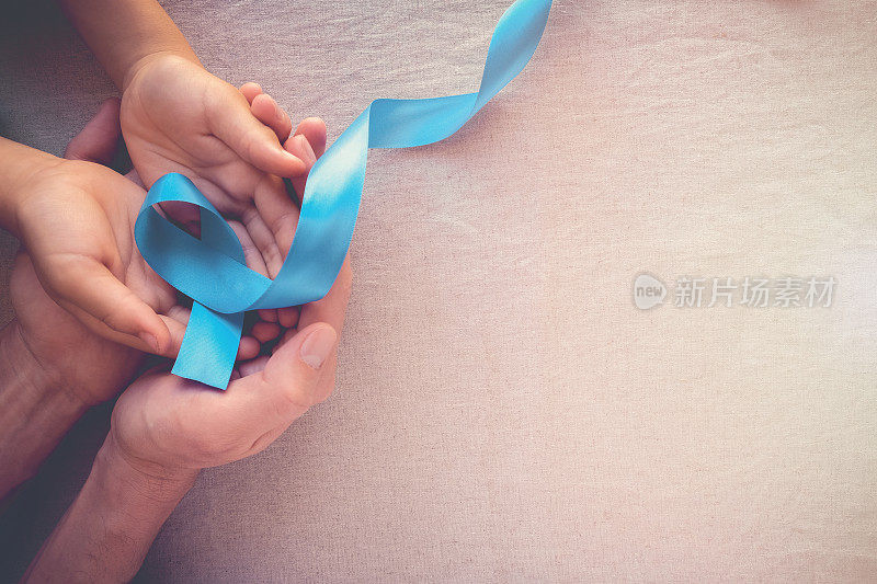 成人和儿童手牵淡蓝色，天蓝色缎带，色调背景，前列腺癌意识和肾上腺皮质癌意识