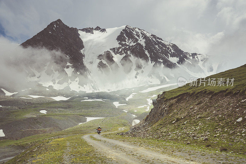 摩托车骑在山路上，朝着一个多雾的冰川。
