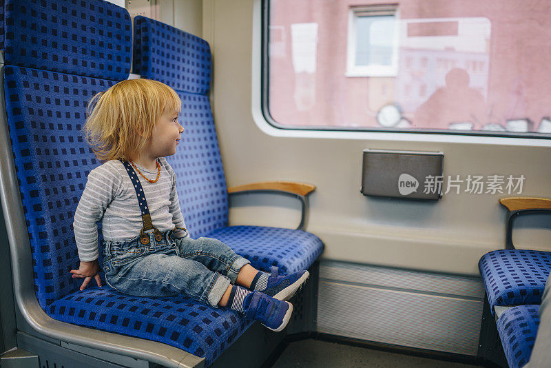 微笑的小男孩在火车上旅行，看着窗外