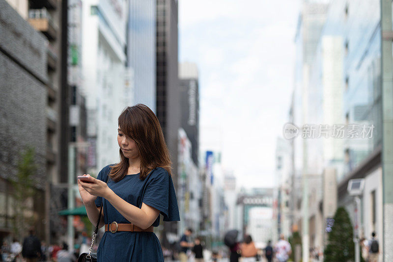 一个女人在购物街上看手机