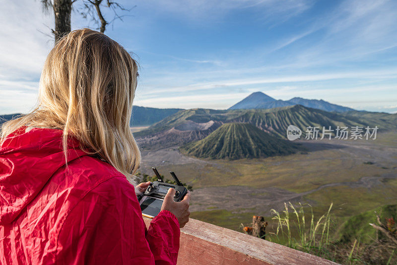 年轻女子使用无人机飞越火山景观——新科技人们旅游的概念