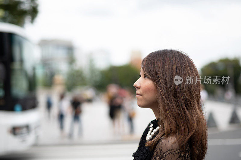一名女子走在原宿车站附近的街道上，原宿是日本著名的观光胜地