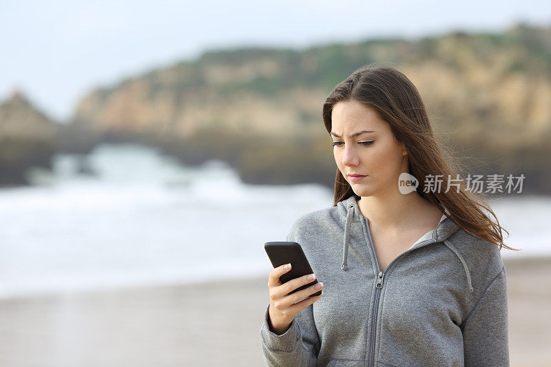 愤怒的青少年在海滩上看手机短信