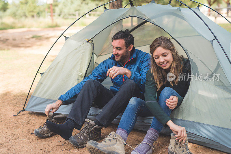 一对野营的年轻夫妇系好他们的靴子准备去远足