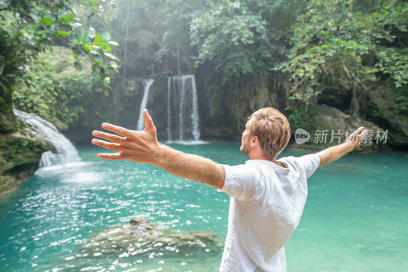 年轻男子在菲律宾拥抱美丽的瀑布