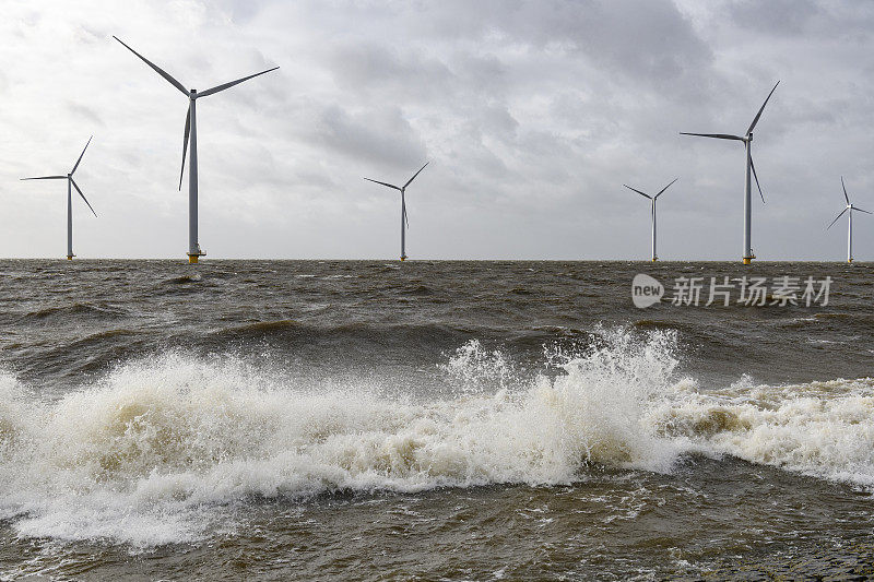 在一场风暴中，一个近海风力公园的风力涡轮机与巨浪袭击海岸