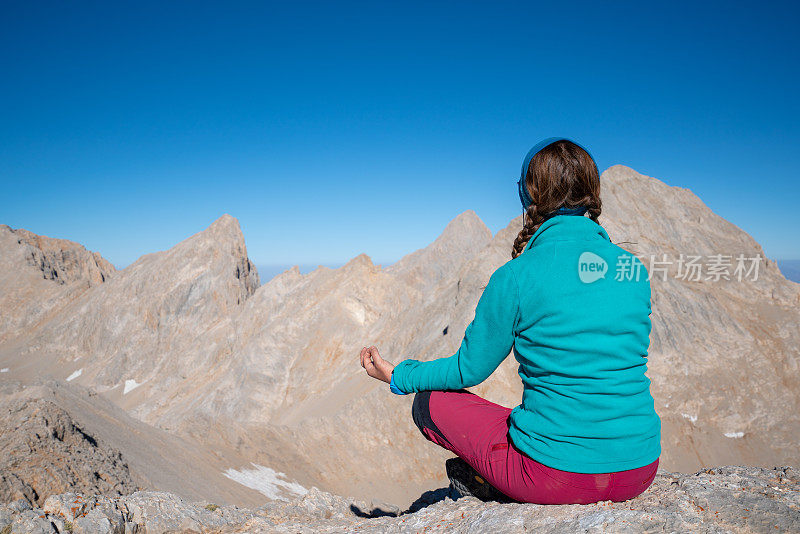 一名年轻的登山者正在一座高海拔的山峰上做瑜伽