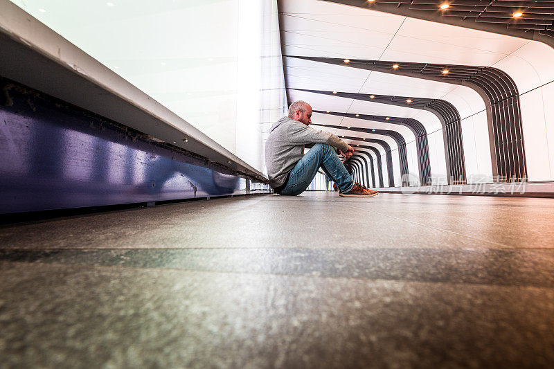 无家可归的年轻人坐在城市的未来主义照明地铁隧道