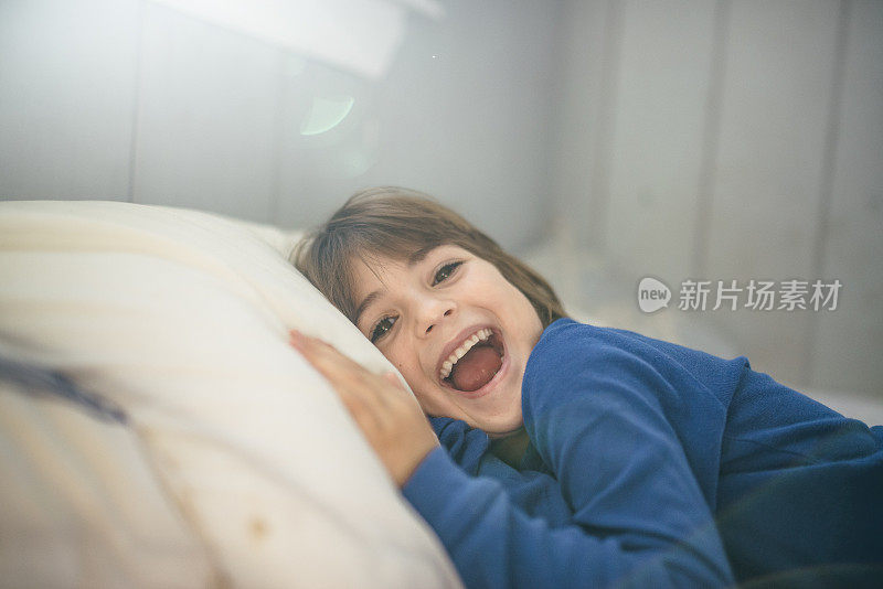 穿着睡衣的孩子傻乎乎地躺在床上开心