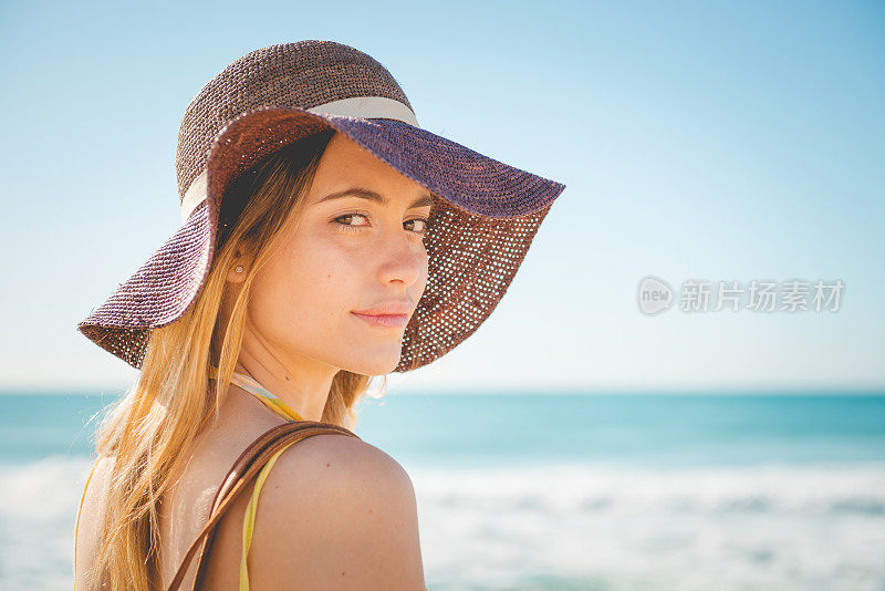 戴草帽的漂亮女孩在海滩上休息