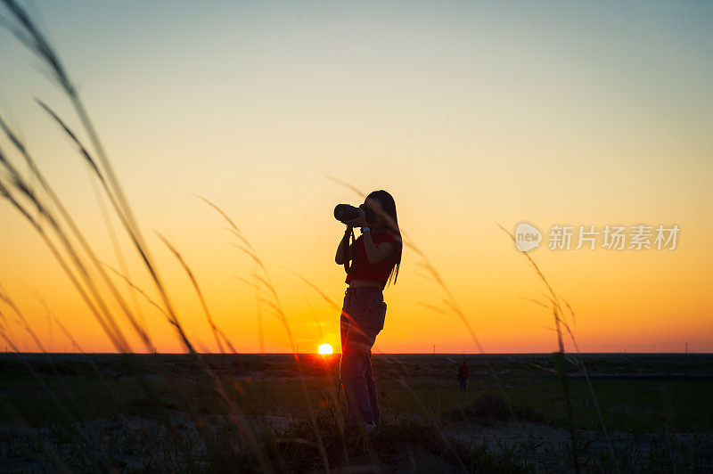 摄影师女孩用单反相机拍摄日落