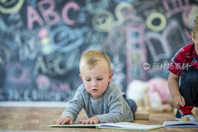 蹒跚学步的孩子在地板上阅读库存照片