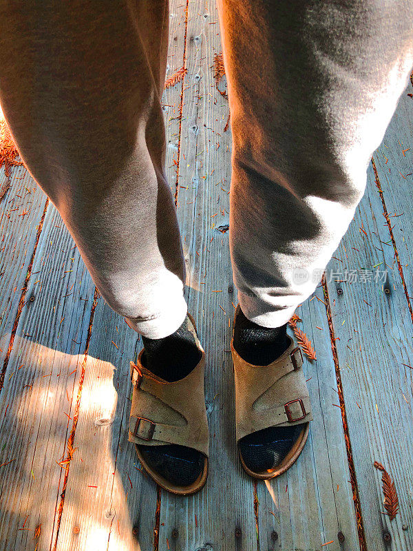 勃肯鞋凉鞋和运动裤:男子站在木制甲板上，袜子