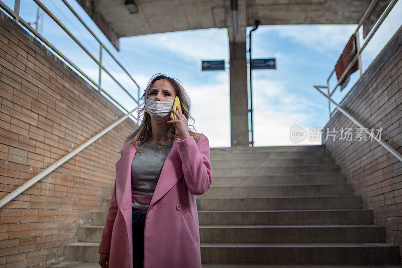 一位戴着防污染口罩的年轻女子正走下火车站的楼梯。