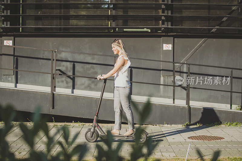 年轻的女商人在城市里骑摩托车