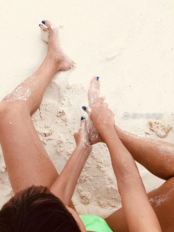 成年女性在沙滩上用沙子剥皮肤