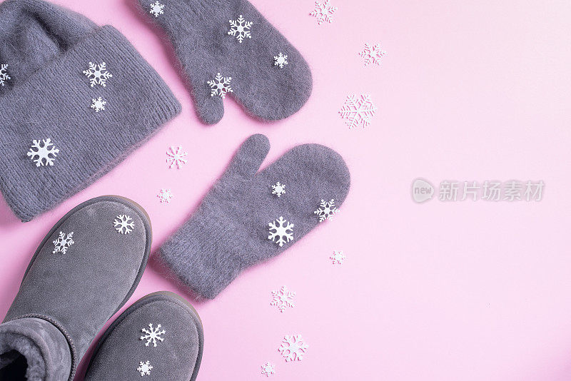 冬天暖和的衣服平躺着。羊毛女性服装毛衣，围巾，靴子，粉红色背景的雪花。俯视图，复制空间