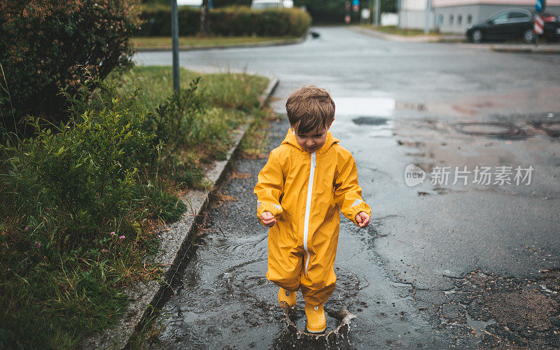 小男孩在雨中玩耍，跳进水里画画