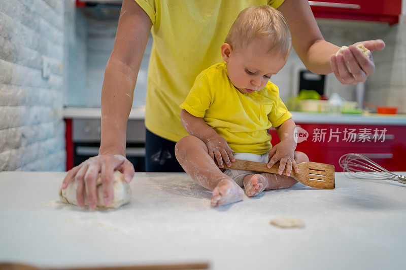 妈妈和儿子正在准备早上一起做饼干的面团。孩子在扔面粉，很高兴。