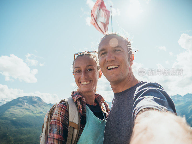 夫妇在山顶上举着瑞士国旗自拍