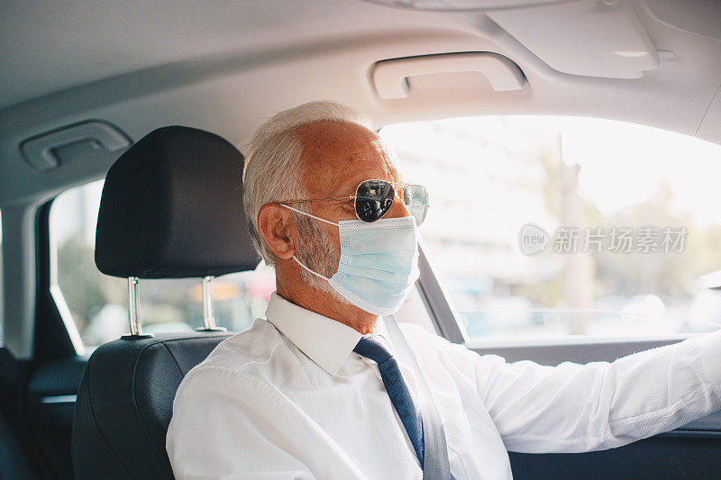 戴着防护面具和手套的老人开车。