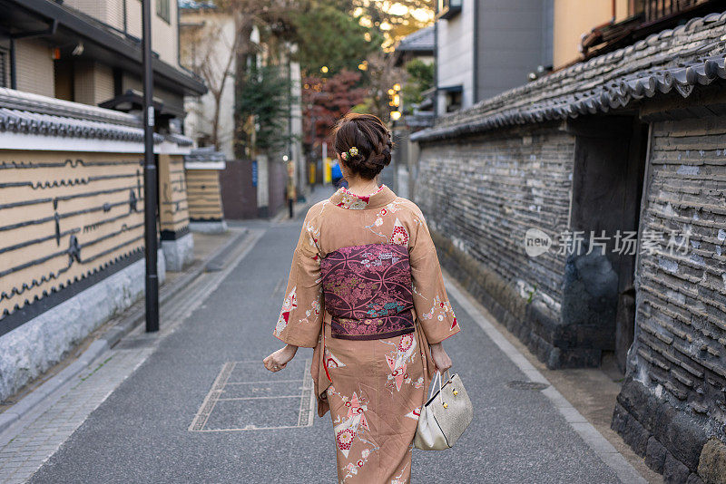 后视图的日本妇女在和服站在狭窄的街道中央