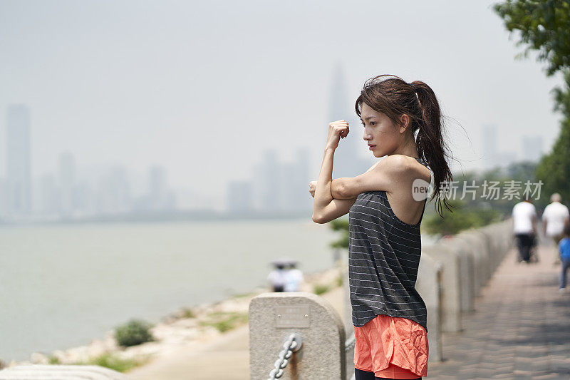 年轻的亚洲女人在户外运动前热身