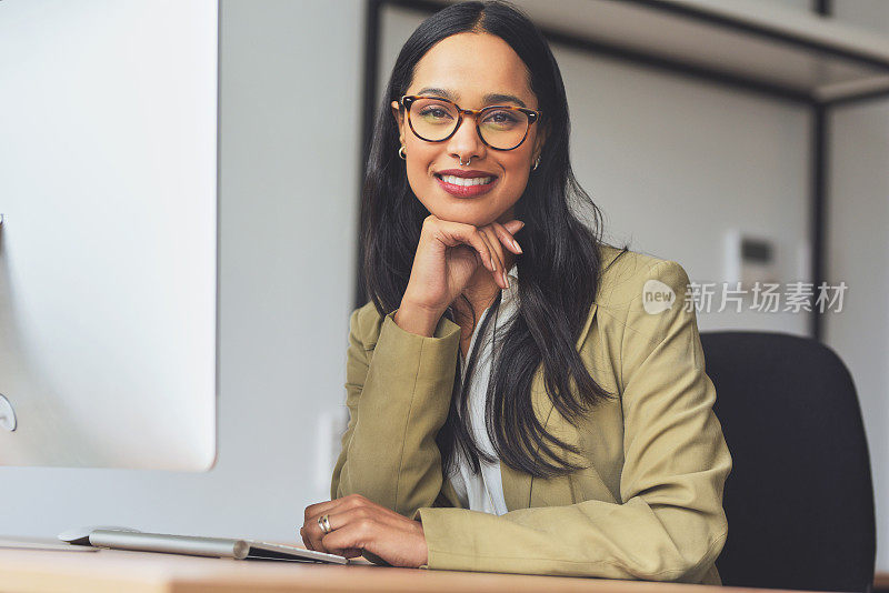 照片中，一位迷人的年轻女商人独自坐在办公室的办公桌前