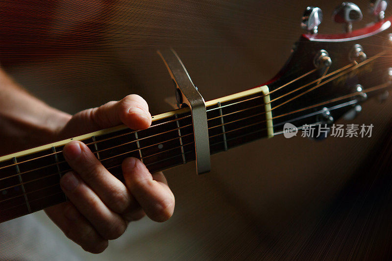 一个男人的手在吉他的指板上，他的手指穿过弦，夹住和弦。器乐，吉他课，乐谱