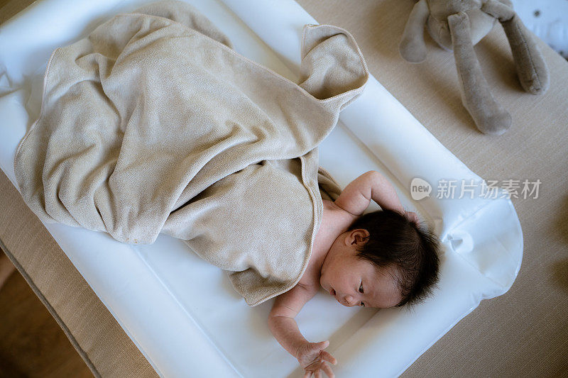 亚洲女新生儿躺在床上和阳光在早上。可爱的小女孩才三周大。微笑，哭泣，扭动，情感概念。