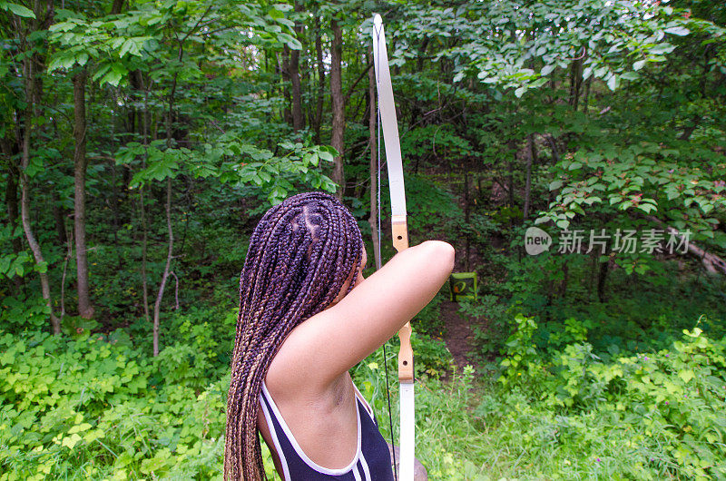 年轻的海地女人正用弓箭瞄准目标