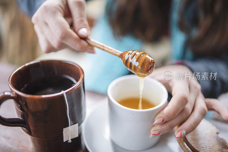 女人把天然蜂蜜放进茶里。