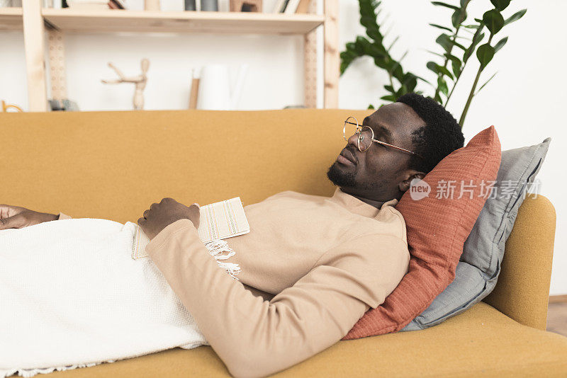 非洲裔美国人看完书在沙发上睡着了