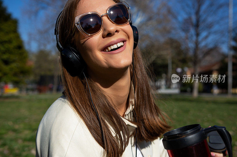 美丽的年轻女子正戴着耳机听音乐。幸福的太阳镜