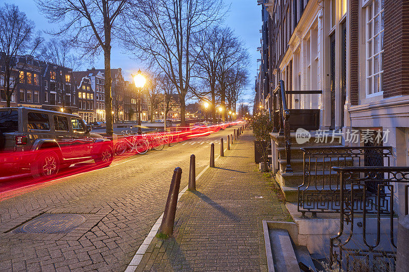黄昏时分，阿姆斯特丹的城市街道上有汽车留下的轻轨