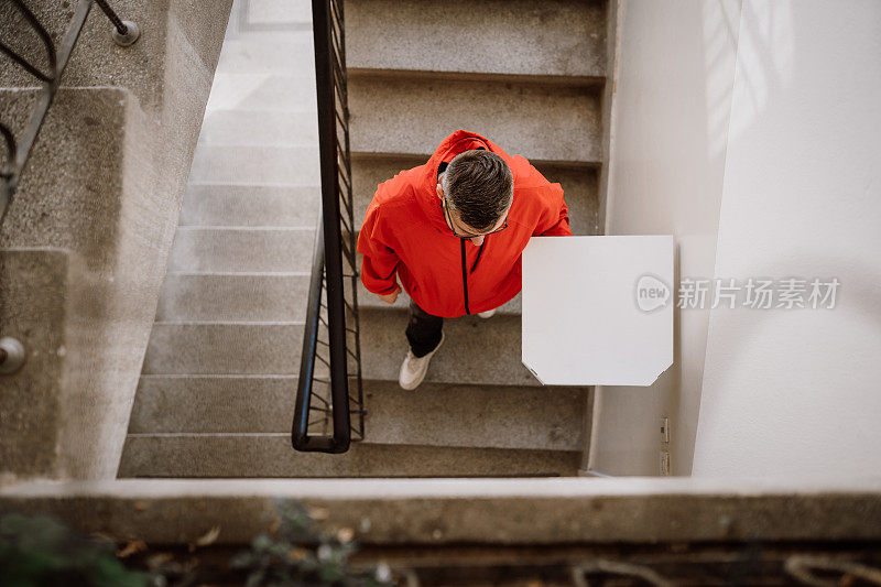 一个白人快递员爬上楼梯