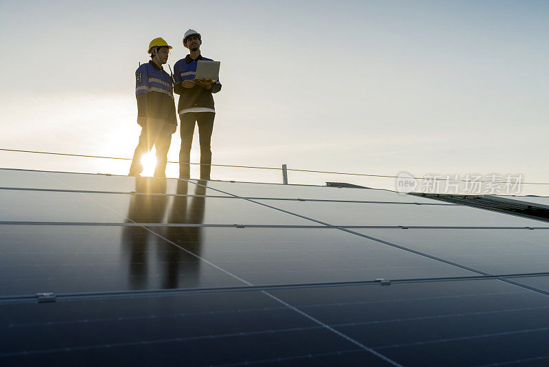 专业技术人员专业工程师带着笔记本电脑和平板电脑维护检查在工厂屋顶阳光下安装太阳能屋顶板。工程师小组调查检查太阳能电池板屋顶。