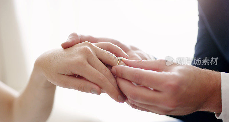 婚姻，戒指和爱之间的丈夫和妻子在他们的仪式上交换结婚戒指。浪漫的男子牵着女子的手求婚，并在答应后赠送订婚戒指
