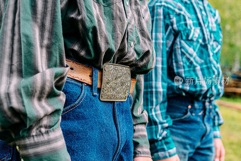 低角度的肖像，一个十几岁的牧场主男孩的皮带扣县博览会冠军从一个牧场比赛，站在他的兄弟旁边的小镇家庭拥有的牧场，美国科罗拉多州